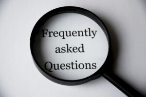 White paper pager with the words Frequently Asked Questions in a magnifying glass